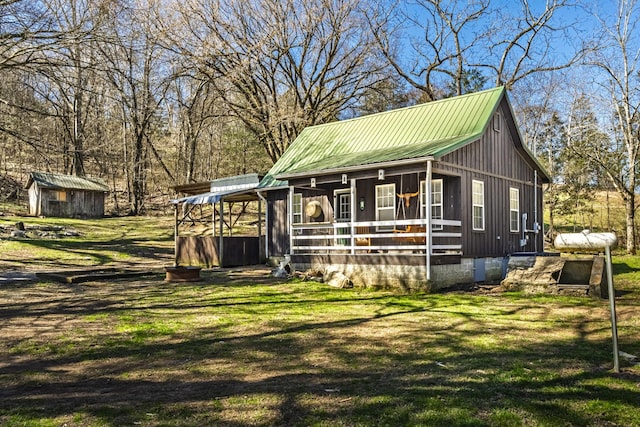 view of front of property with a front yard, metal roof, and an outdoor structure