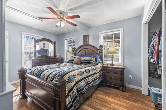 bedroom featuring attic access, multiple windows, a textured ceiling, and wood finished floors