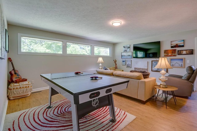 recreation room with light wood-style flooring and a textured ceiling