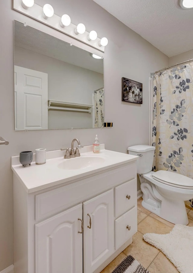 bathroom with toilet, vanity, a textured ceiling, and tile patterned floors