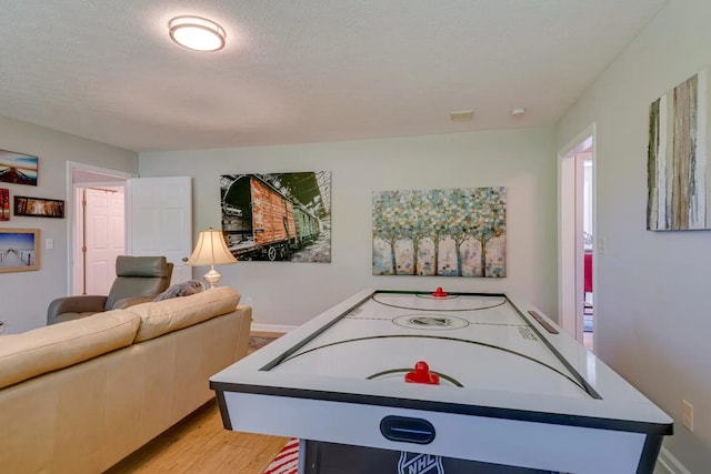 playroom with light wood-type flooring, baseboards, and a textured ceiling