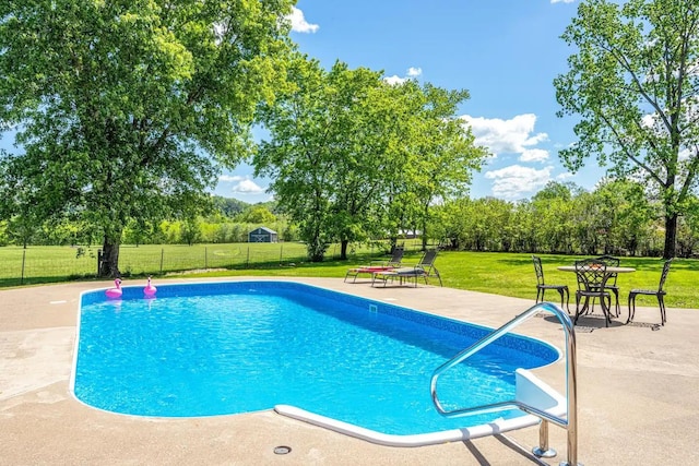 view of swimming pool featuring a patio, a lawn, fence, and a fenced in pool