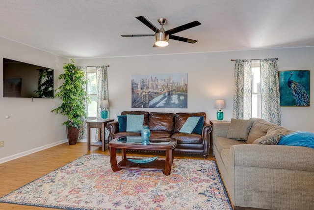 living area featuring baseboards, plenty of natural light, a ceiling fan, and wood finished floors