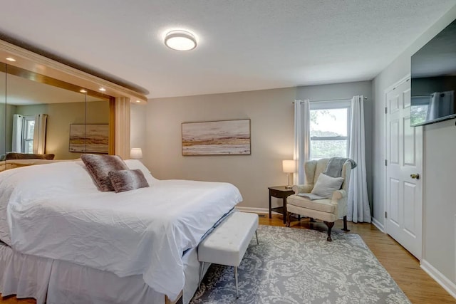 bedroom featuring a textured ceiling, baseboards, and wood finished floors