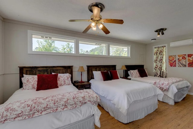 bedroom featuring ceiling fan, an AC wall unit, and light wood-type flooring