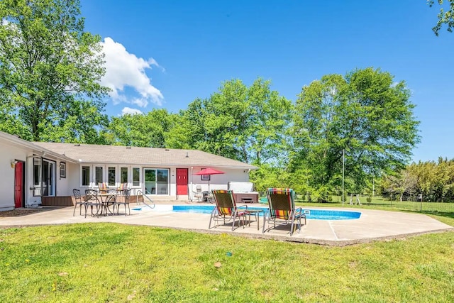 back of property with an outdoor pool, a patio, and a lawn