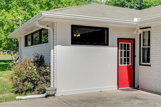 entrance to property with brick siding and a shingled roof