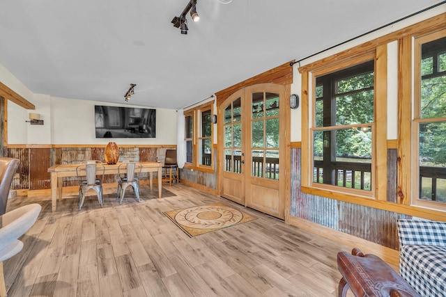 interior space with rail lighting, wainscoting, wood walls, and wood finished floors