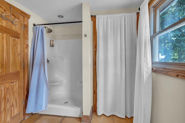 bathroom with curtained shower and tile patterned flooring