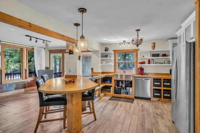 dining area featuring plenty of natural light, light wood-style flooring, and an inviting chandelier