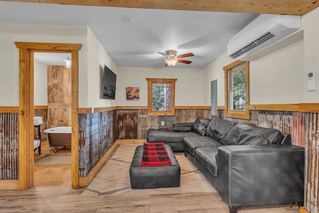 living room with wainscoting, ceiling fan, wood finished floors, a wall mounted air conditioner, and wood walls