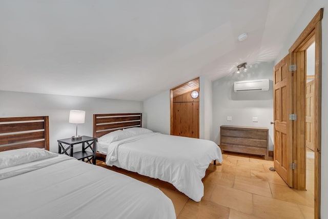 bedroom featuring vaulted ceiling, a wall mounted air conditioner, and stone tile floors