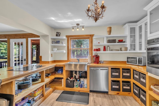 kitchen with light wood finished floors, open shelves, stainless steel appliances, white cabinetry, and a sink