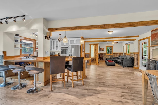 interior space featuring a wall unit AC, a fireplace, wood tiled floor, wainscoting, and ceiling fan