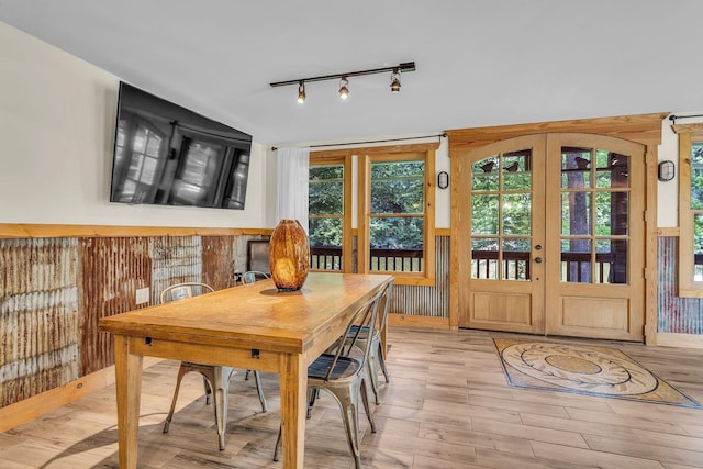 dining area with track lighting, wood finished floors, and french doors