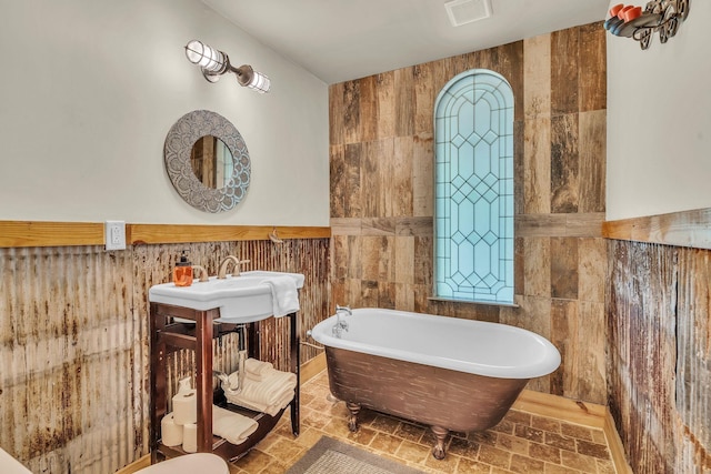 bathroom with visible vents, a freestanding bath, and tile walls