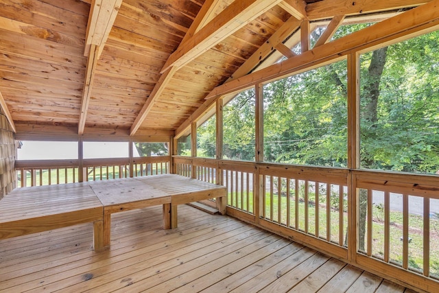 unfurnished sunroom featuring vaulted ceiling with beams, wooden ceiling, and a forest view