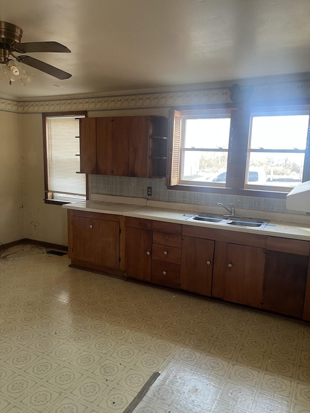 kitchen featuring decorative backsplash, brown cabinets, light countertops, open shelves, and a sink