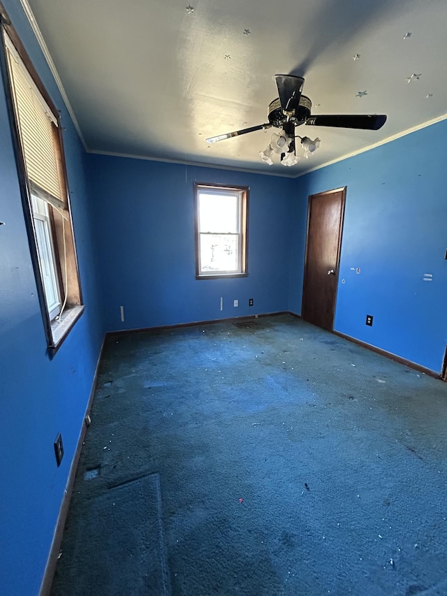 carpeted empty room with a ceiling fan, crown molding, and baseboards