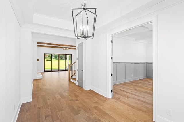 hallway with light wood-style floors, crown molding, stairway, and a notable chandelier