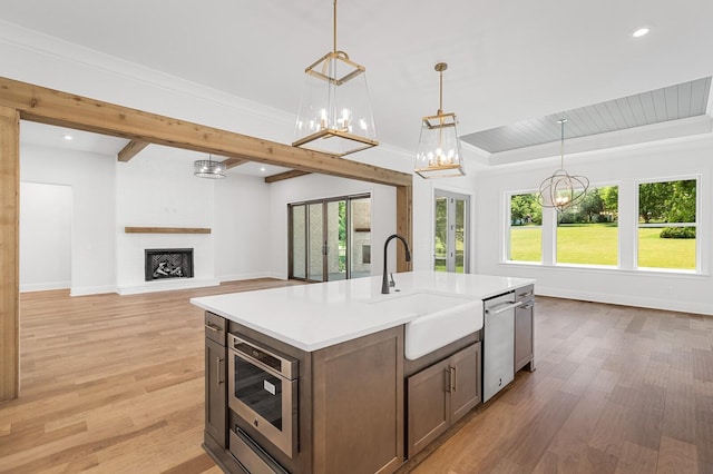 kitchen with a large fireplace, dishwasher, built in microwave, light countertops, and a sink