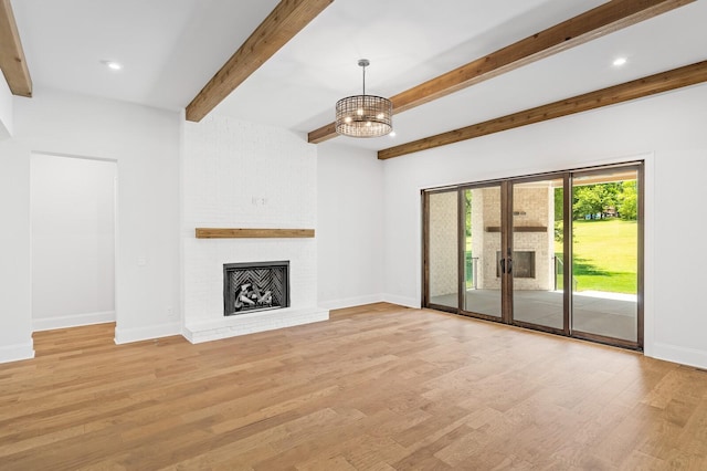 unfurnished living room with light wood-type flooring, a brick fireplace, baseboards, and a notable chandelier