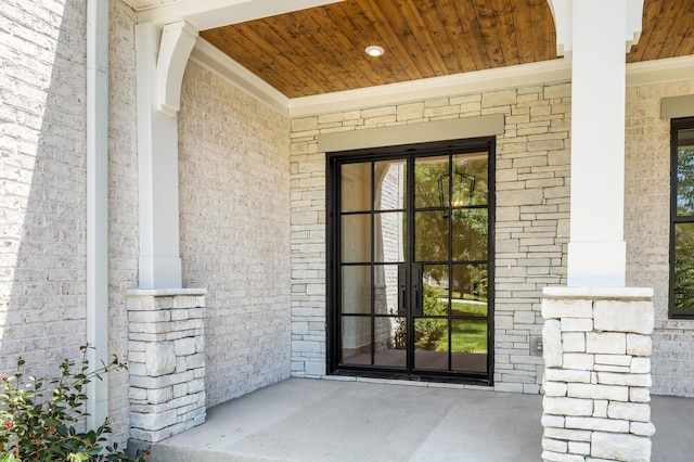 doorway to property featuring a porch and brick siding