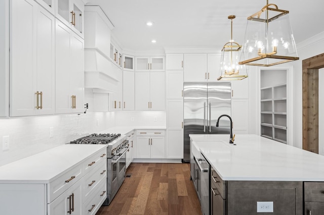 kitchen featuring premium appliances, a kitchen island with sink, and light countertops