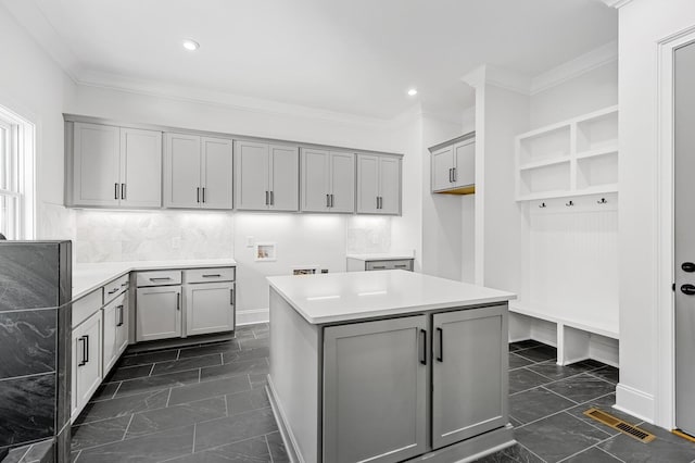 kitchen with crown molding, a kitchen island, visible vents, and gray cabinetry