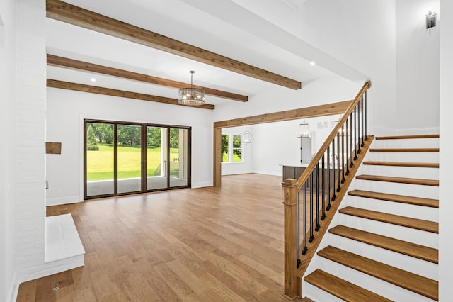 unfurnished living room with baseboards, stairway, wood finished floors, and a notable chandelier