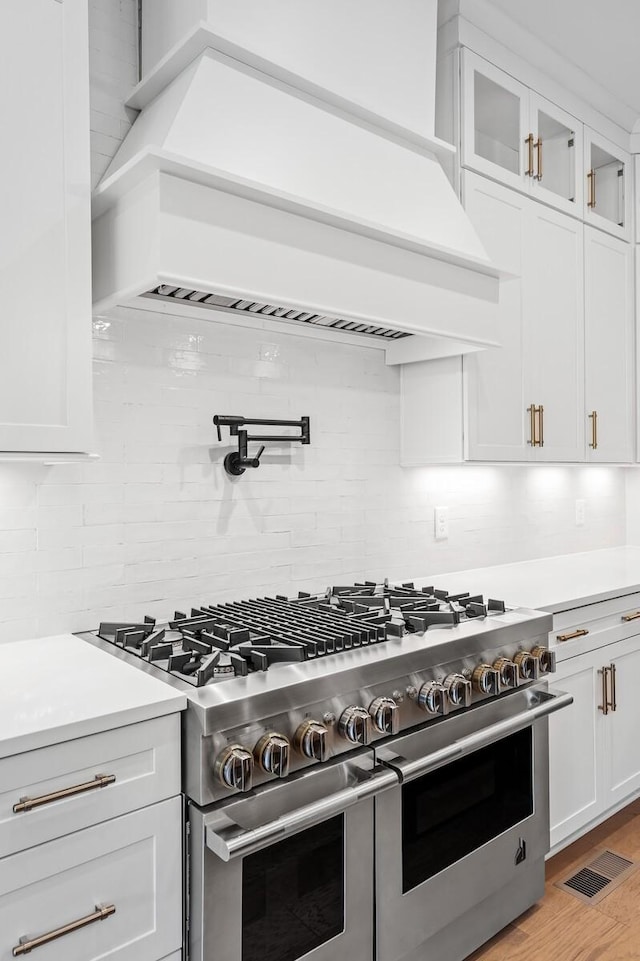 kitchen with white cabinets, light countertops, visible vents, and double oven range