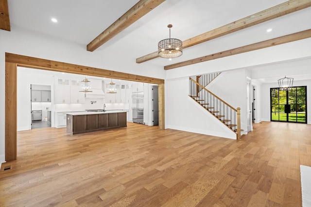 unfurnished living room featuring stairway, a chandelier, and light wood-style floors