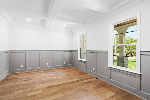 empty room with a decorative wall, beamed ceiling, coffered ceiling, and light wood-style floors