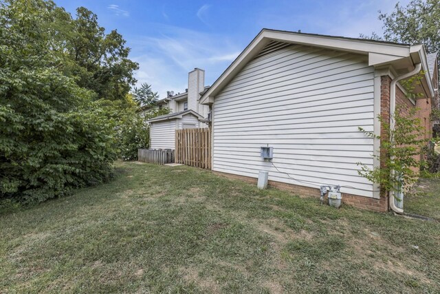 view of side of property featuring fence and a yard