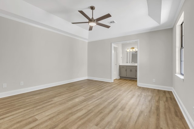 unfurnished bedroom with visible vents, a raised ceiling, light wood-style flooring, and baseboards