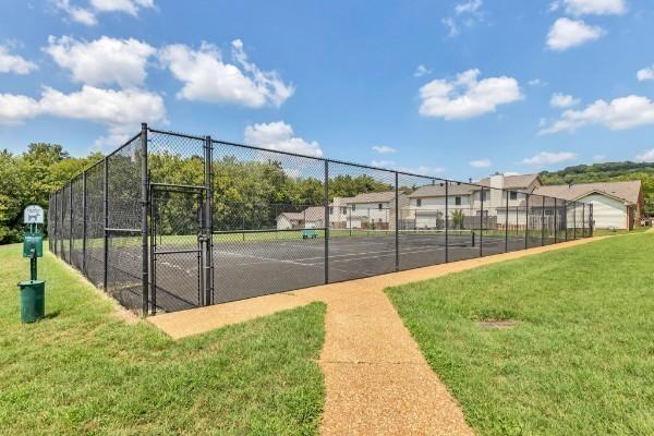 view of sport court with a lawn, fence, and a gate