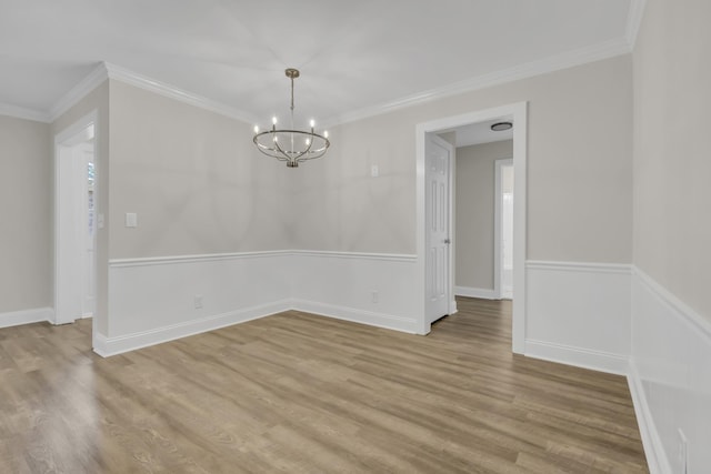 empty room with a notable chandelier, ornamental molding, and light wood-style floors