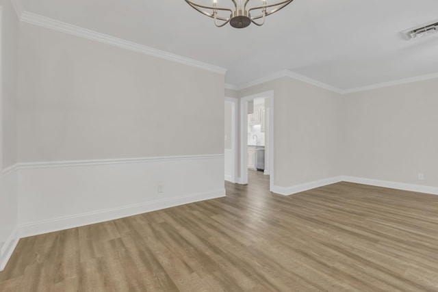 spare room featuring ornamental molding, visible vents, an inviting chandelier, and wood finished floors