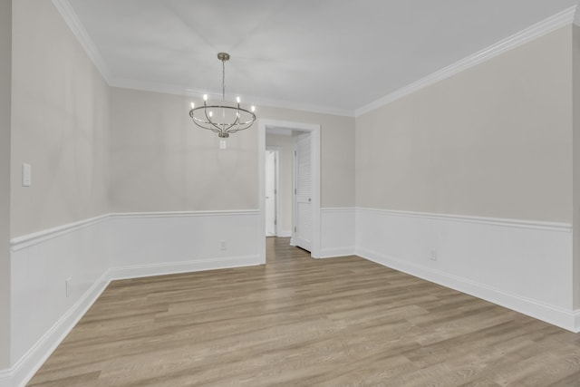 unfurnished dining area featuring ornamental molding, light wood-type flooring, a wainscoted wall, and an inviting chandelier