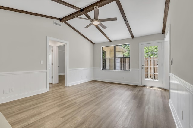 spare room with lofted ceiling with beams, a wainscoted wall, light wood-type flooring, and visible vents