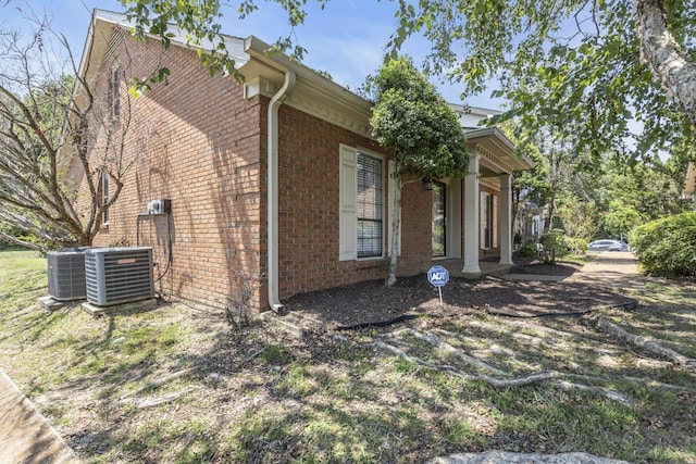 view of side of property featuring brick siding and central air condition unit