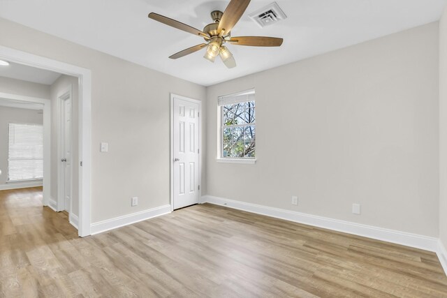 spare room with ceiling fan, light wood-type flooring, visible vents, and baseboards