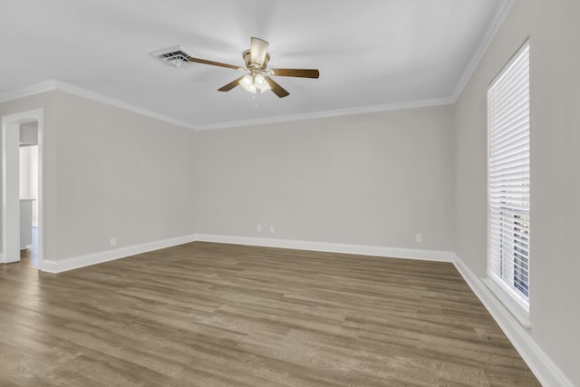 spare room featuring ceiling fan, wood finished floors, visible vents, baseboards, and ornamental molding