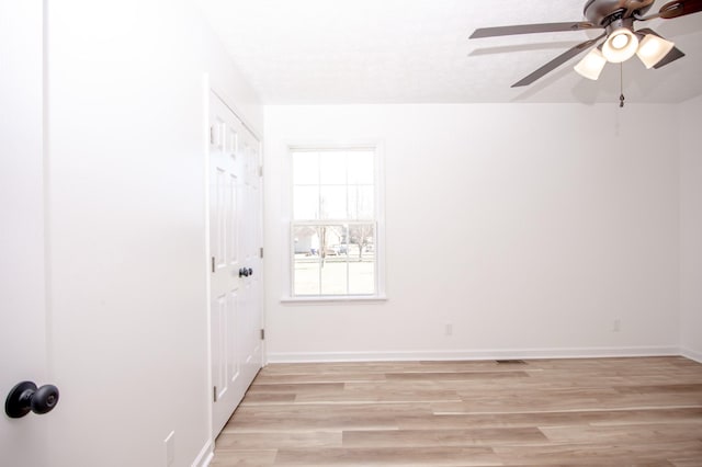 empty room featuring ceiling fan, visible vents, light wood-style flooring, and baseboards