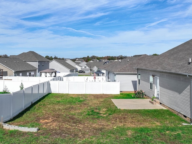 view of yard with a residential view, a fenced backyard, and a patio