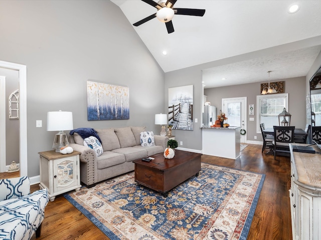 living area featuring dark wood-type flooring, a healthy amount of sunlight, high vaulted ceiling, and baseboards