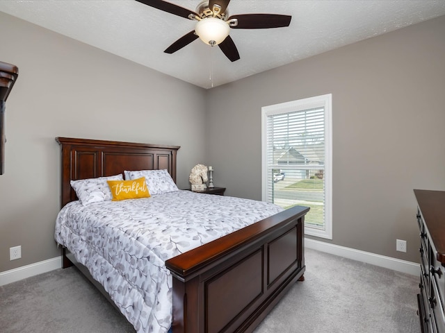 bedroom featuring light carpet, a ceiling fan, and baseboards