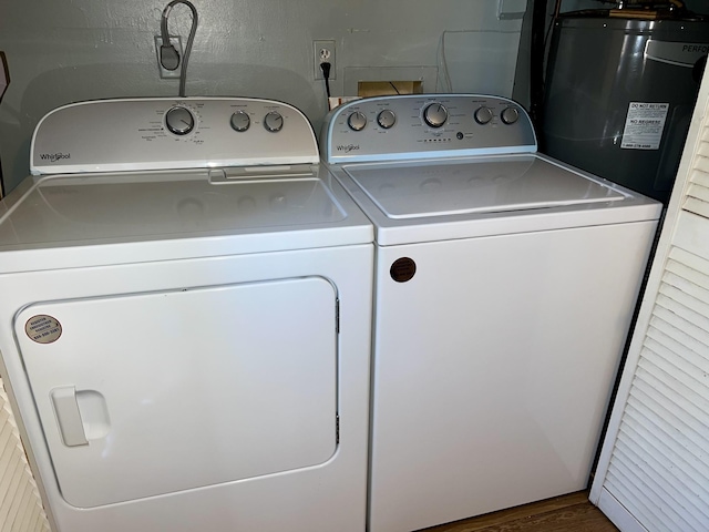 washroom featuring laundry area, water heater, washer and clothes dryer, and wood finished floors