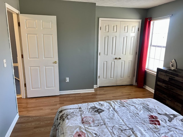 bedroom with a closet, wood finished floors, and baseboards