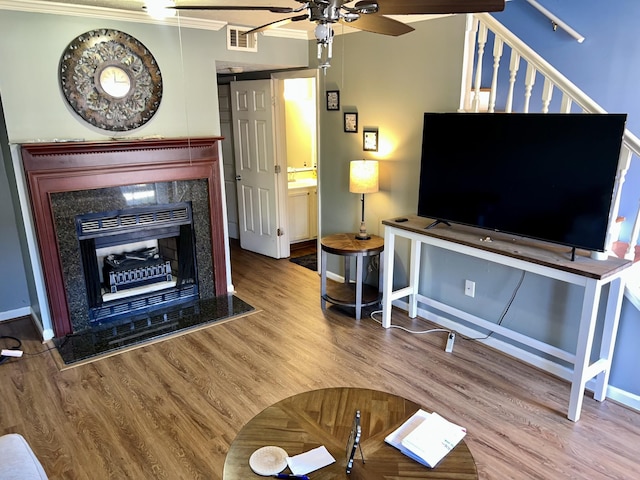 unfurnished living room with a ceiling fan, a high end fireplace, visible vents, and wood finished floors